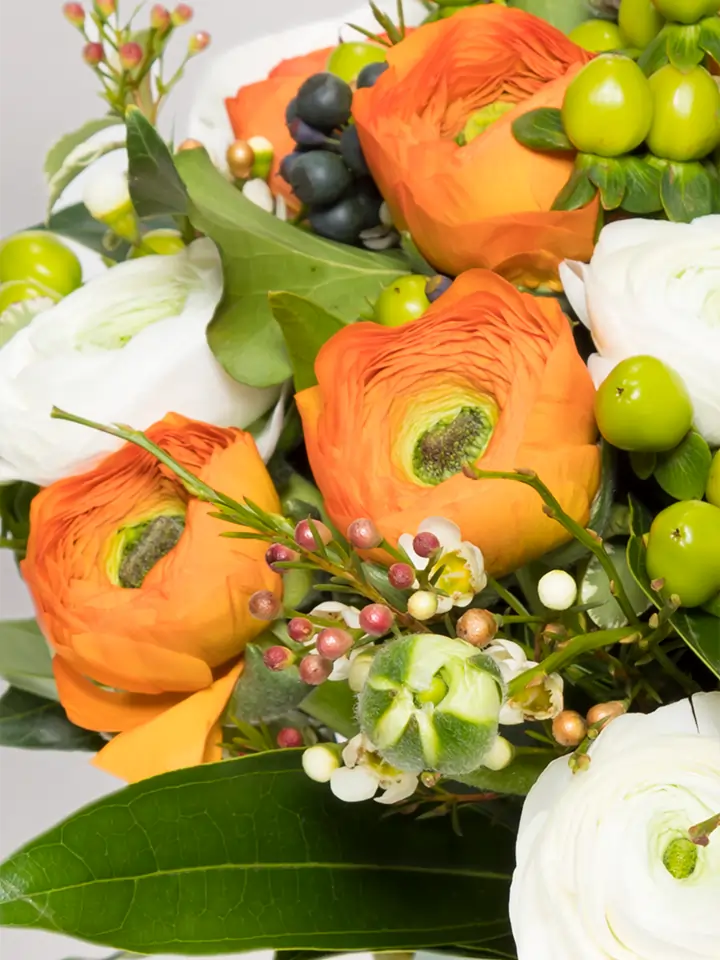 Bouquet ranuncoli arancio e bianchi e bacche verde macro